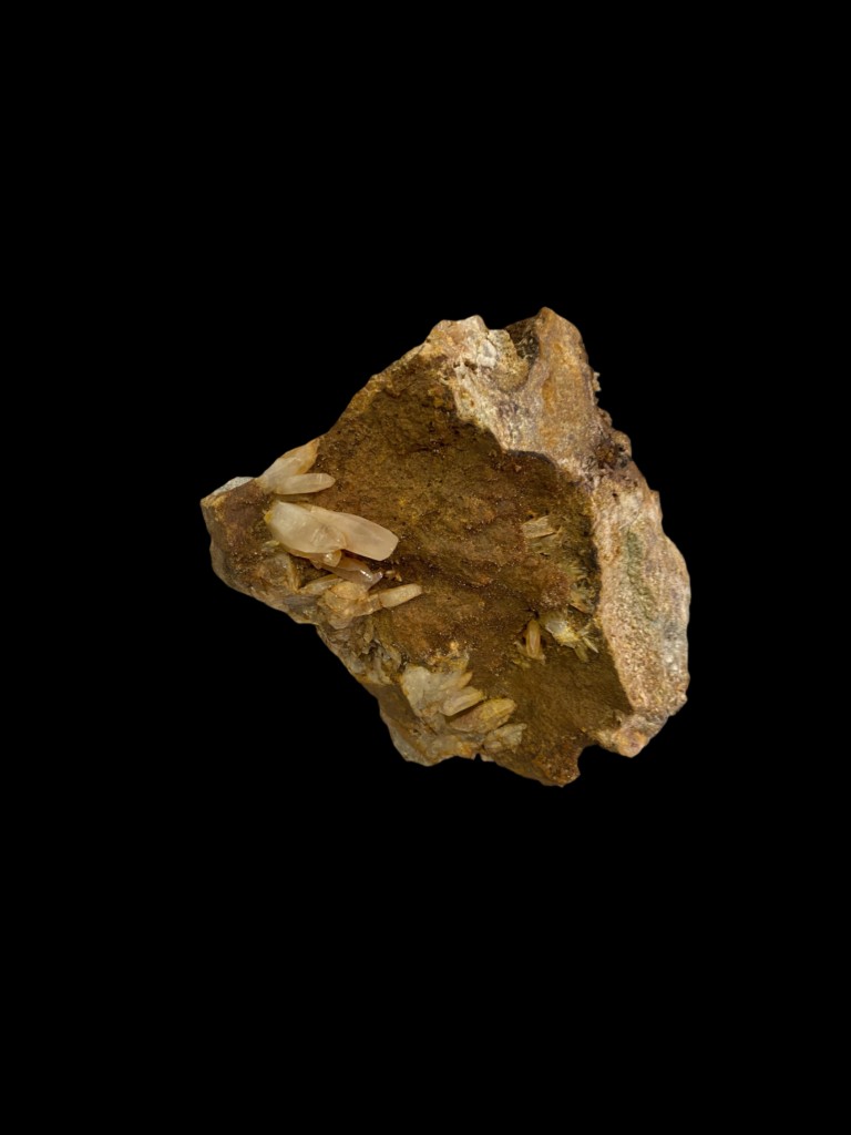 Cristales prismáticos translúcidos emergiendo de matriz ferruginosa ocre